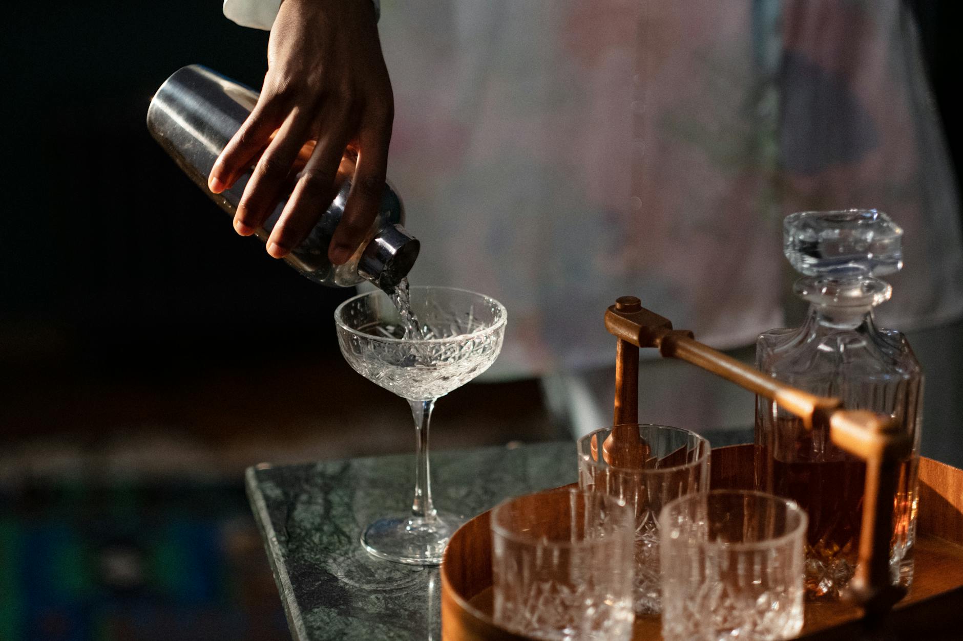 Barman przelewa koktajl z shakera do szklanki w domowym barze